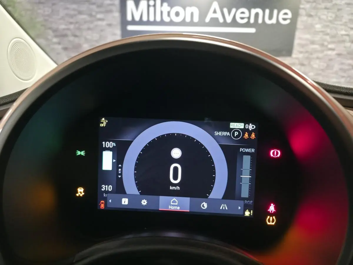 Vue rapprochée du tableau de bord numérique de la Fiat 500 Cabriolet électrique rose, affichant 0 km/h et l'autonomie restante.