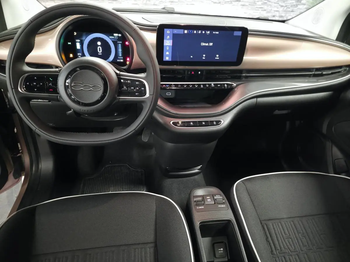 Vue intérieure avant de la Fiat 500 Cabriolet électrique 2023, planche de bord rose métallisé et volant noir Soft-Touch.