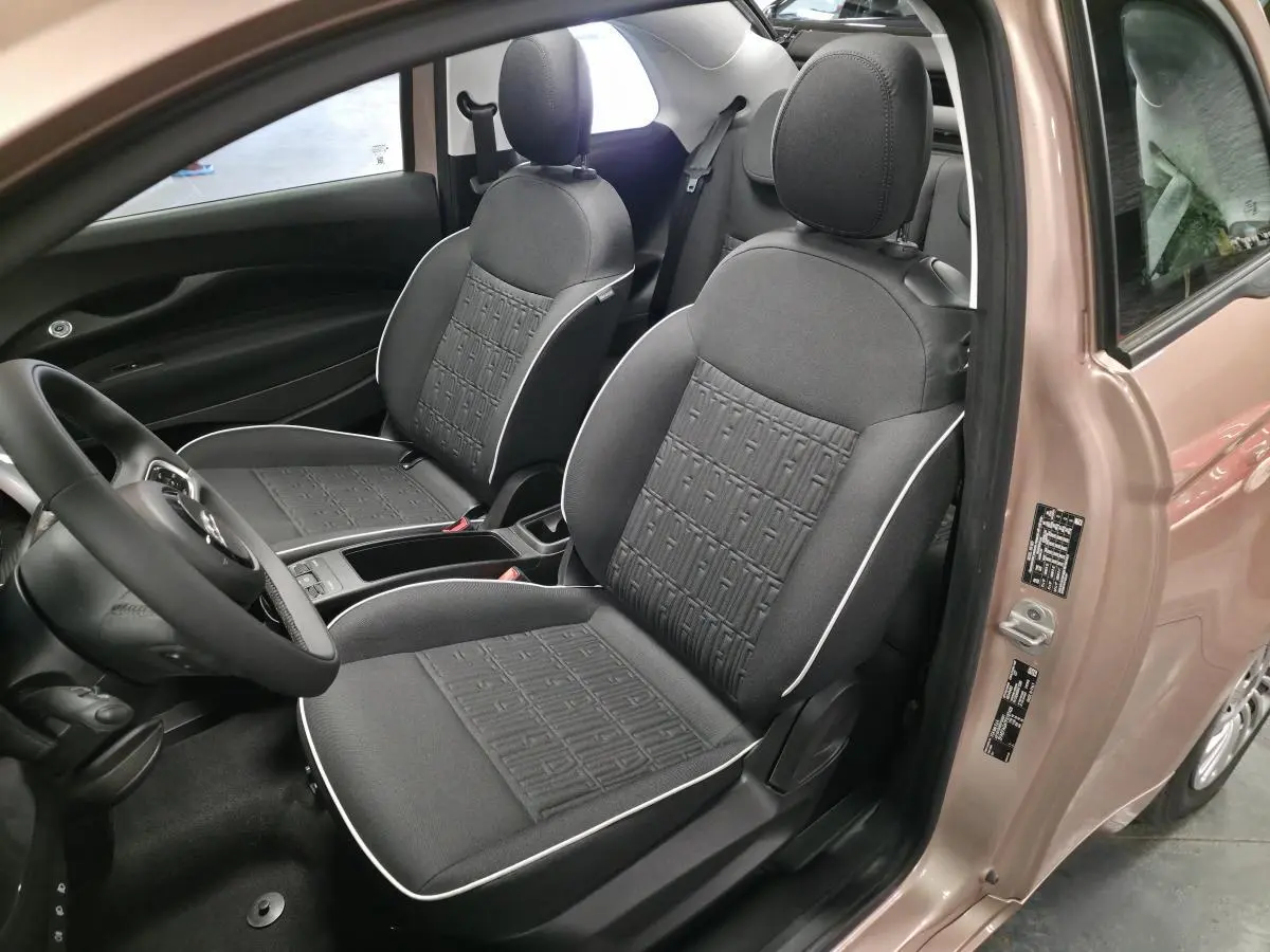Vue intérieure côté conducteur de la FIAT 500 Cabriolet électrique rose, avec sellerie noire et volant soft-touch.