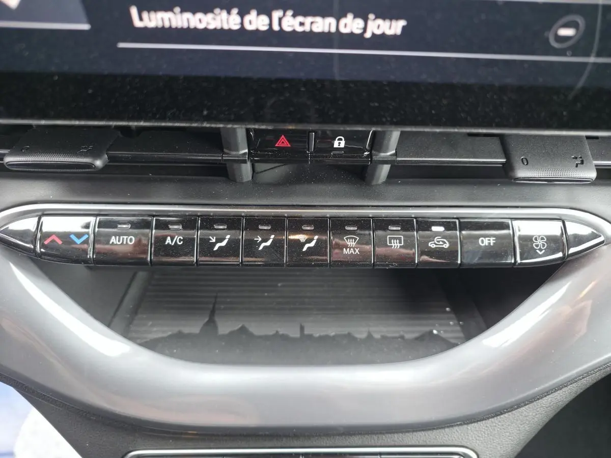 Vue rapprochée des commandes de climatisation automatique sur la planche de bord grise du Fiat 500 Cabriolet électrique rose.