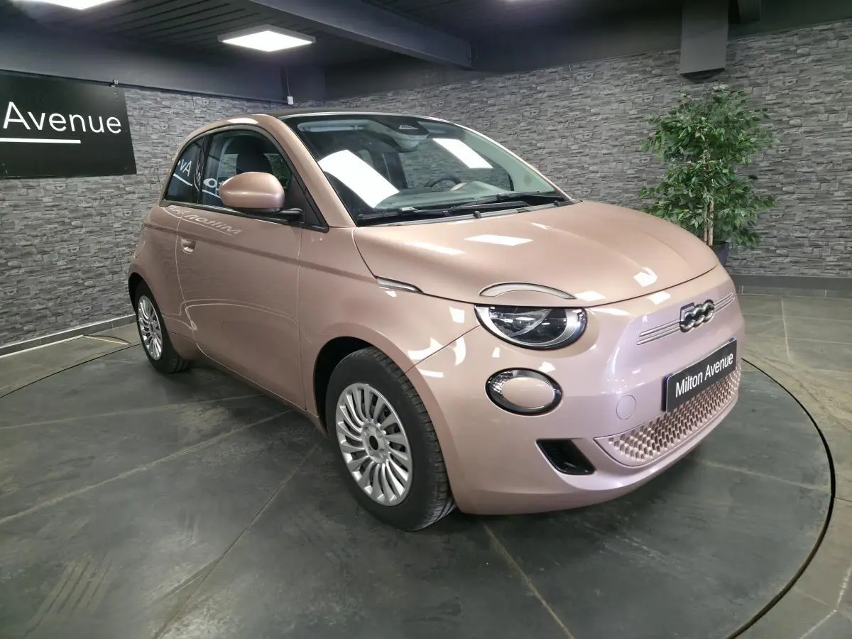 Vue 3/4 avant droite d'une Fiat 500 Cabriolet électrique rose métallisée avec jantes acier et capote noire fermée.