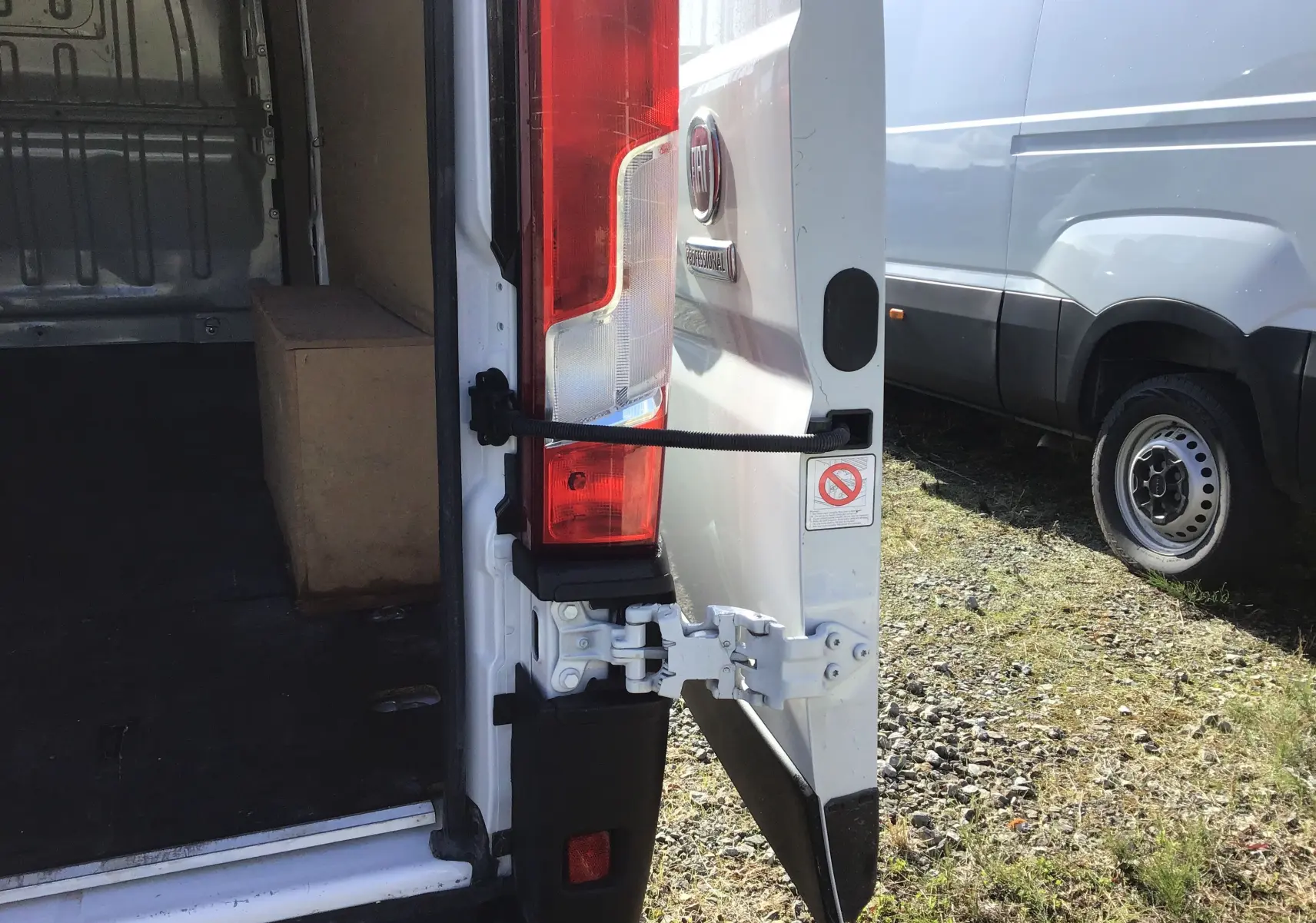 Vue arrière droite du FIAT Ducato Fourgon blanc 2024 avec porte ouverte dévoilant l'intérieur vide et un caisson en bois.