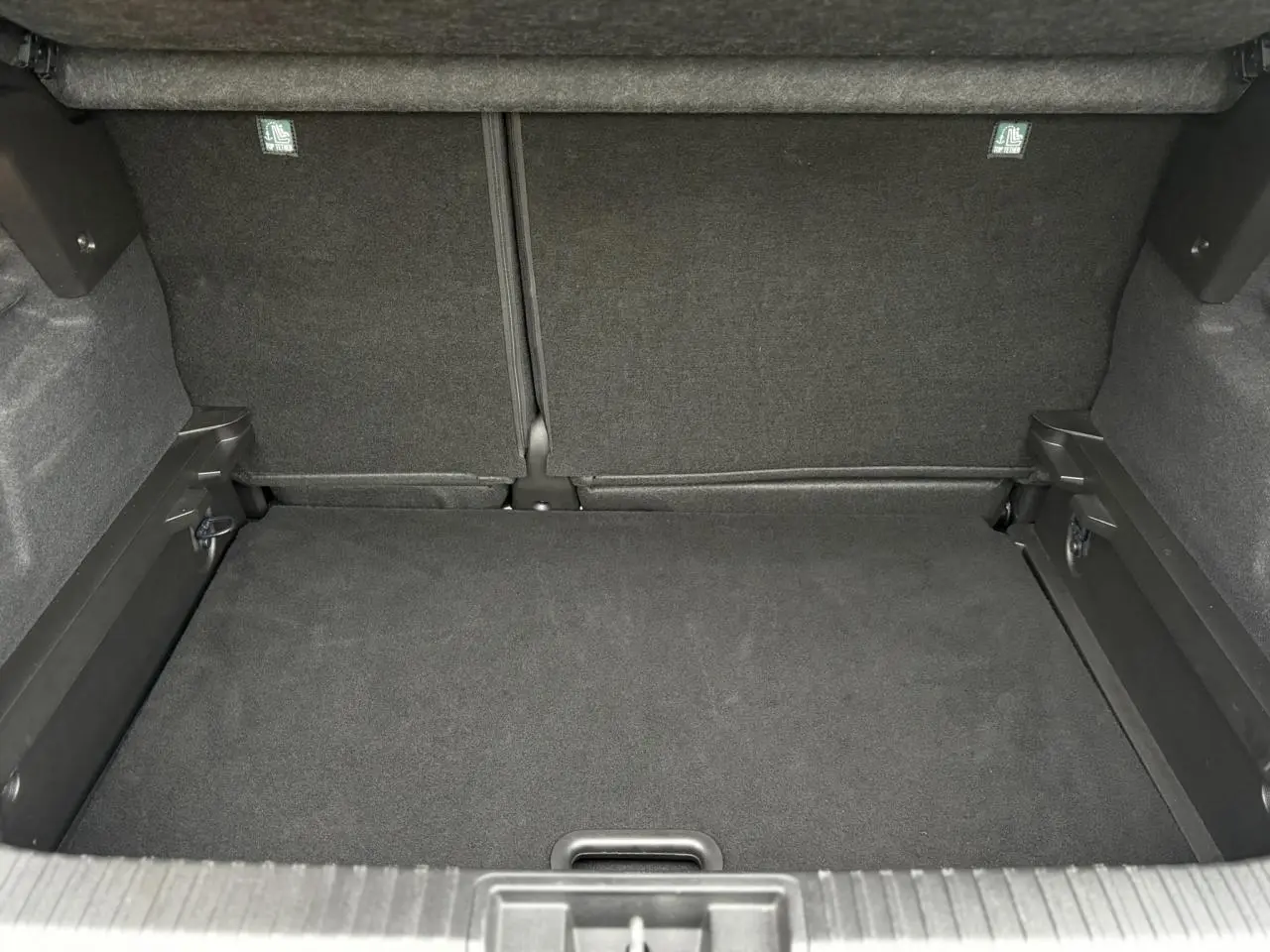 Coffre spacieux du Renault Captur 2025 vu de face, revêtement noir avec plancher plat et fixations ISOFIX visibles.