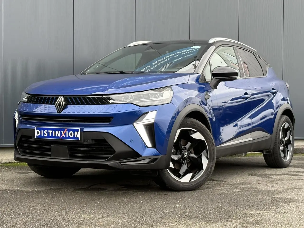 Renault Captur 2025 bleu Iron et noir, vue 3/4 avant droit, jantes alu noires diamantées et railing de toit alu visibles.