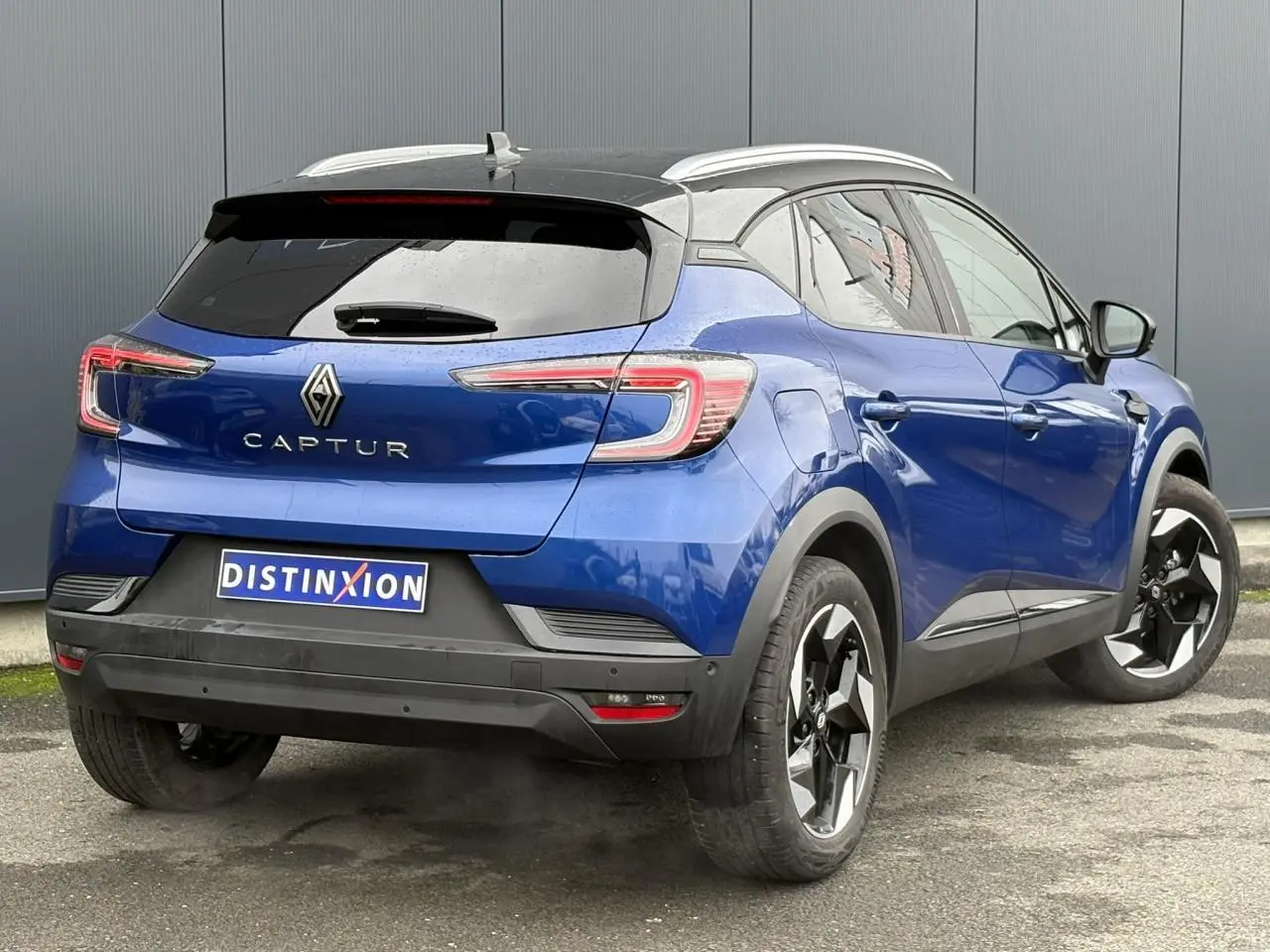 Vue 3/4 arrière droite d'un Renault Captur 2025 bleu Iron et toit noir avec jantes alu 18 pouces diamantées noires.