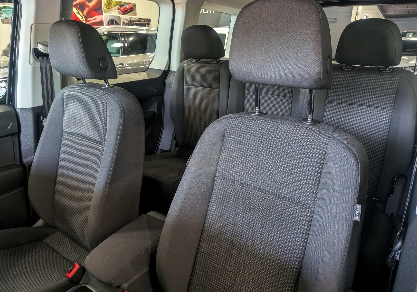 Vue intérieure du Volkswagen Caddy 2025 montrant les sièges tissu gris foncé avec appuie-têtes et ceinture de sécurité.