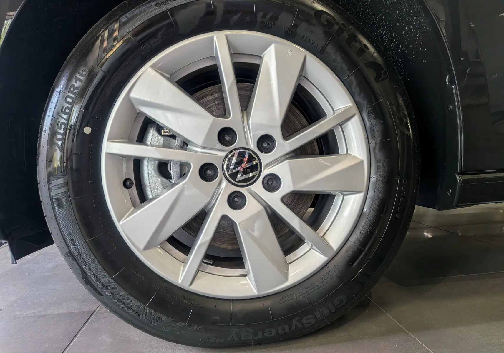 Gros plan sur la jante alliage argentée du Volkswagen Caddy noir 2025, mettant en valeur le logo VW central.