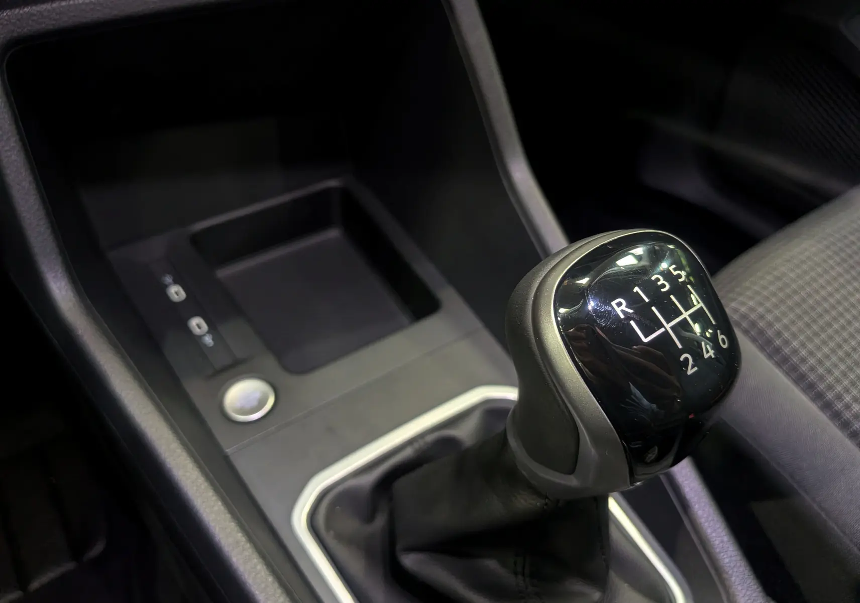 Gros plan sur le levier de vitesses manuel noir du Volkswagen Caddy 2.0 TDI 102 CH, intérieur tissu gris.