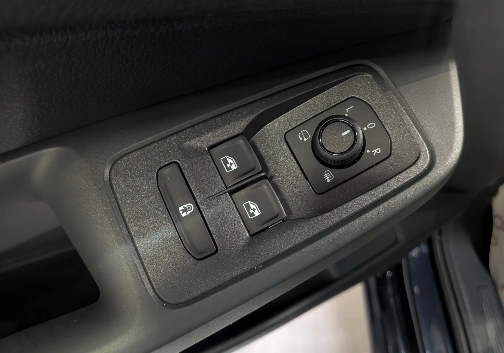 Gros plan sur les commandes de réglage des rétroviseurs et des vitres côté conducteur du Volkswagen Caddy noir 2025.