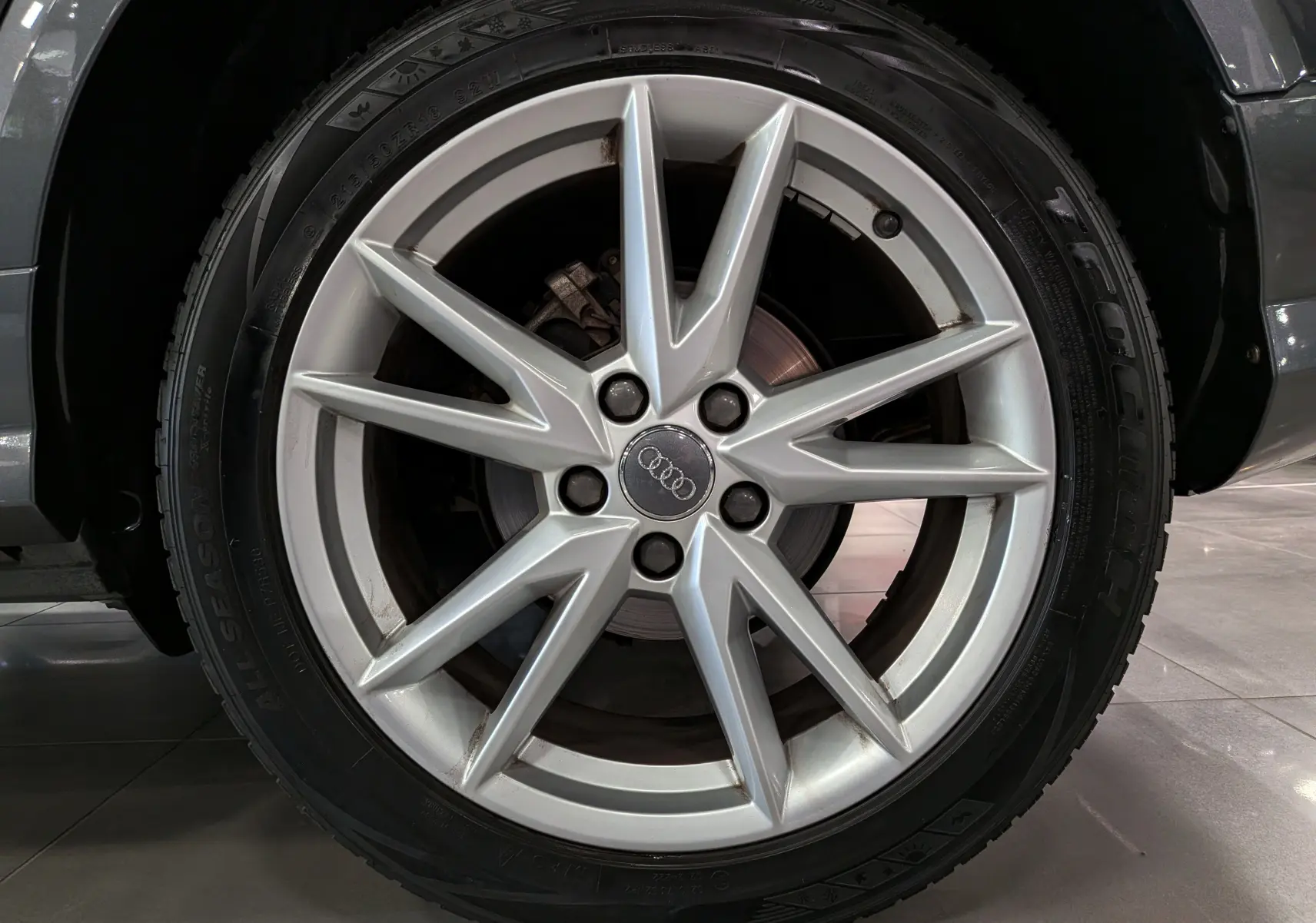 Gros plan sur la jante argentée à dix branches de l'Audi Q2 gris, mettant en valeur le logo Audi au centre.