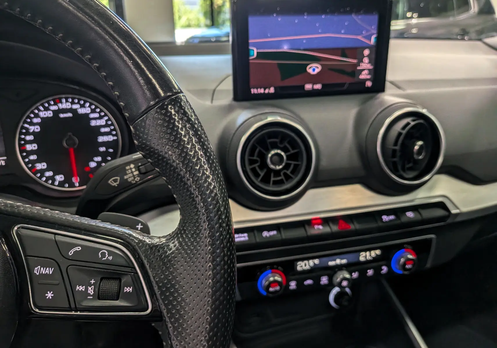Intérieur de l'Audi Q2 2017, vue rapprochée du volant cuir noir et du tableau de bord avec écran de navigation et aérateurs ronds.