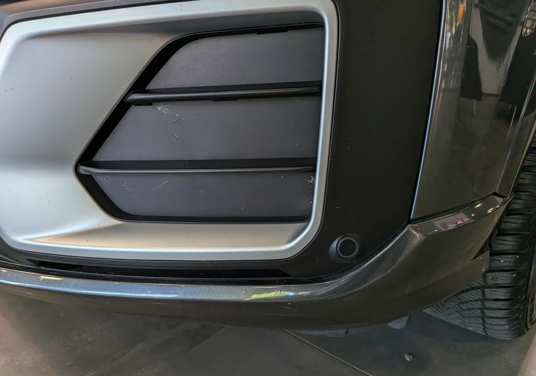 Gros plan sur la partie avant droite grise de l'Audi Q2 1.4 TFSI S-Line, mettant en valeur la grille d'aération et le pare-chocs.