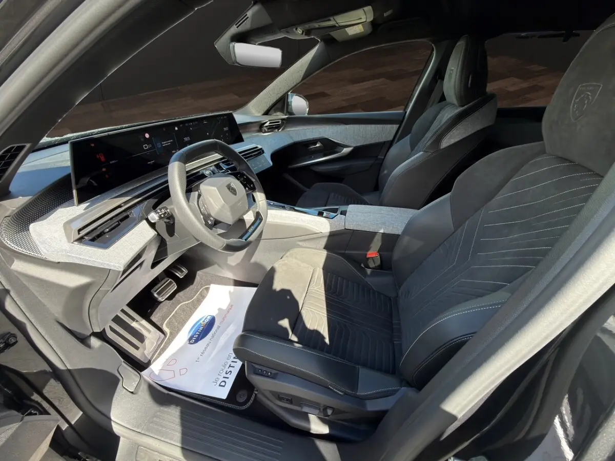 Vue intérieure côté conducteur du Peugeot 5008 gris foncé, avec sièges Alcantara et tableau de bord numérique large.