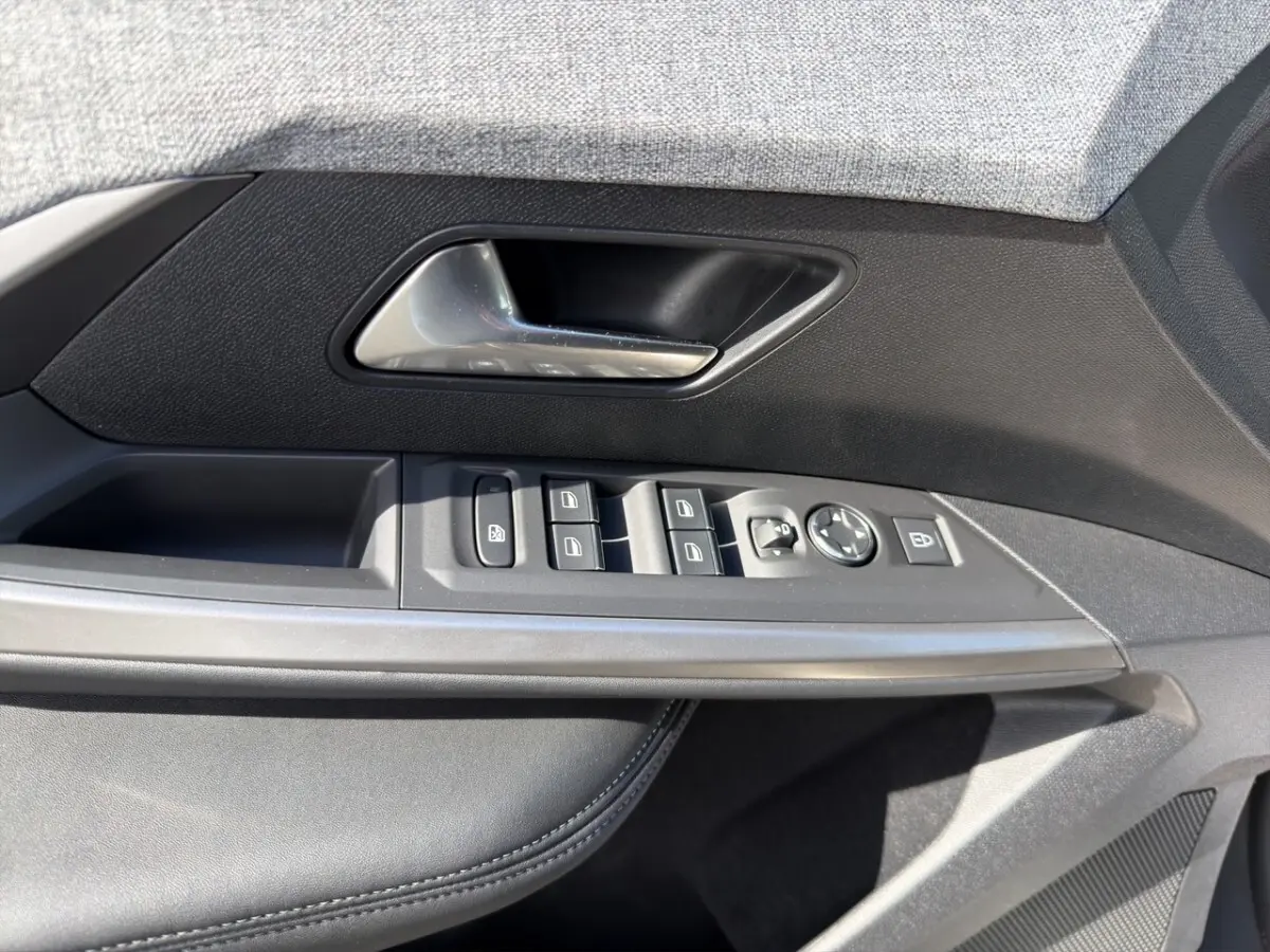 Gros plan sur la porte côté conducteur du Peugeot 5008 gris foncé, montrant les commandes des vitres et rétroviseurs.