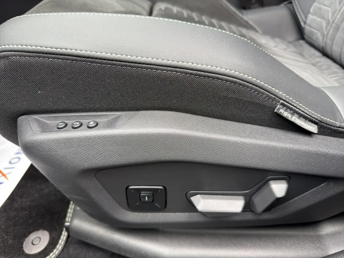 Gros plan sur la commande de réglage électrique du siège avant en cuir et tissu noir du Peugeot 5008 gris foncé.