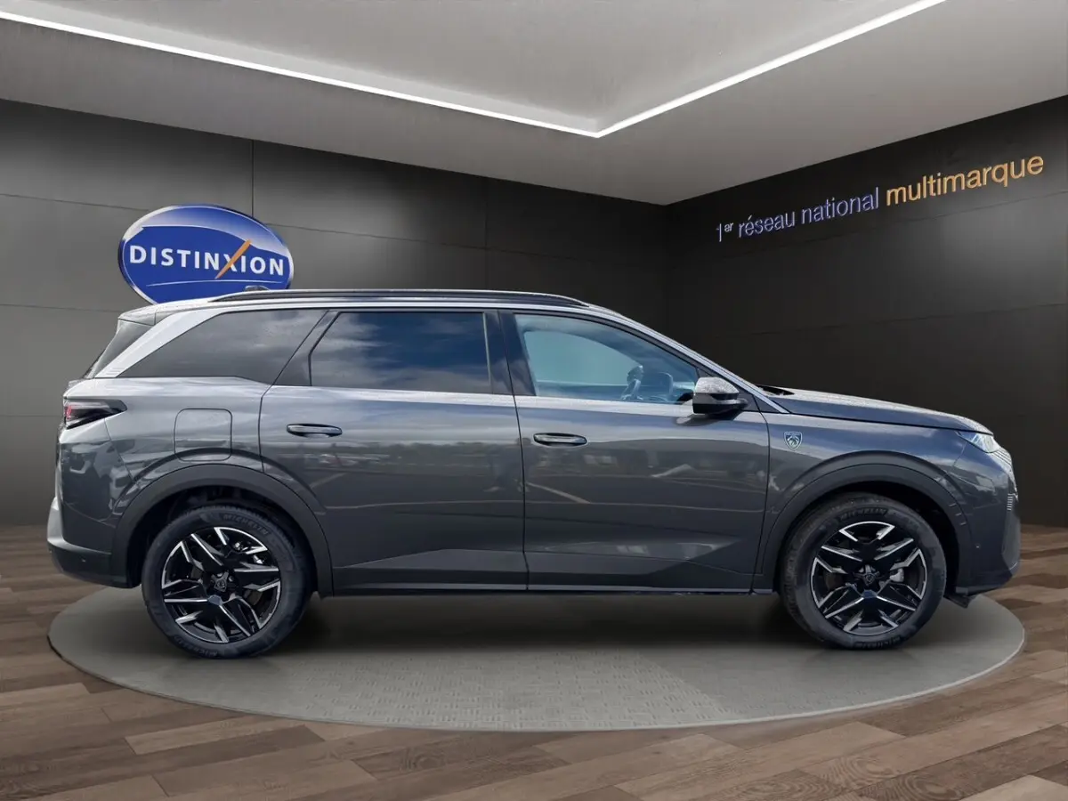 Vue latérale droite du Peugeot 5008 gris foncé avec jantes noires et toit équipé de rails assortis.