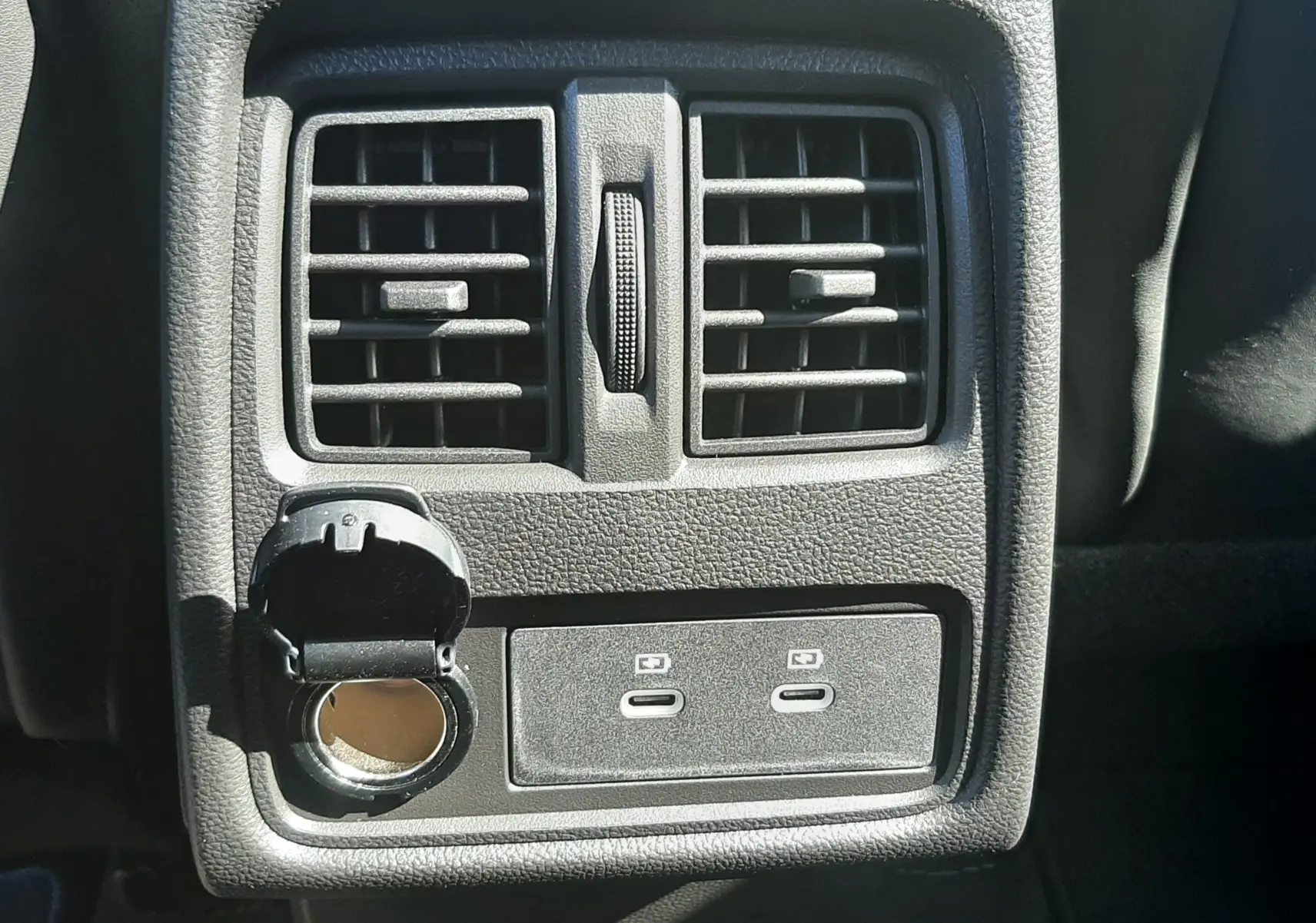 Détail de la console arrière avec prises USB-C et prise allume-cigare ouverte dans un Renault Symbioz gris Cassiopée.