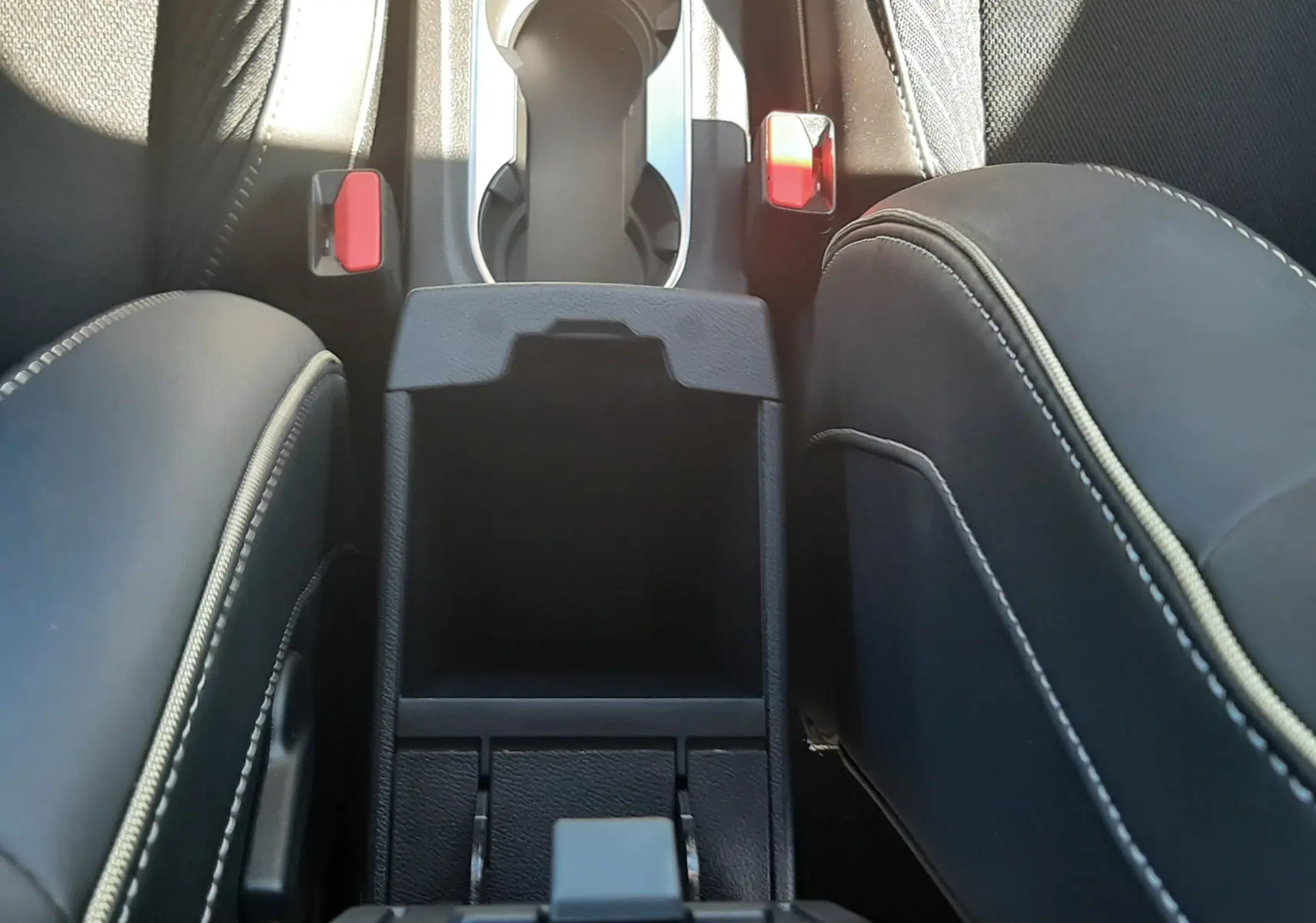 Vue plongeante sur la console centrale noire et les sièges en tissu noir avec surpiqûres blanches du Renault Symbioz hybride.