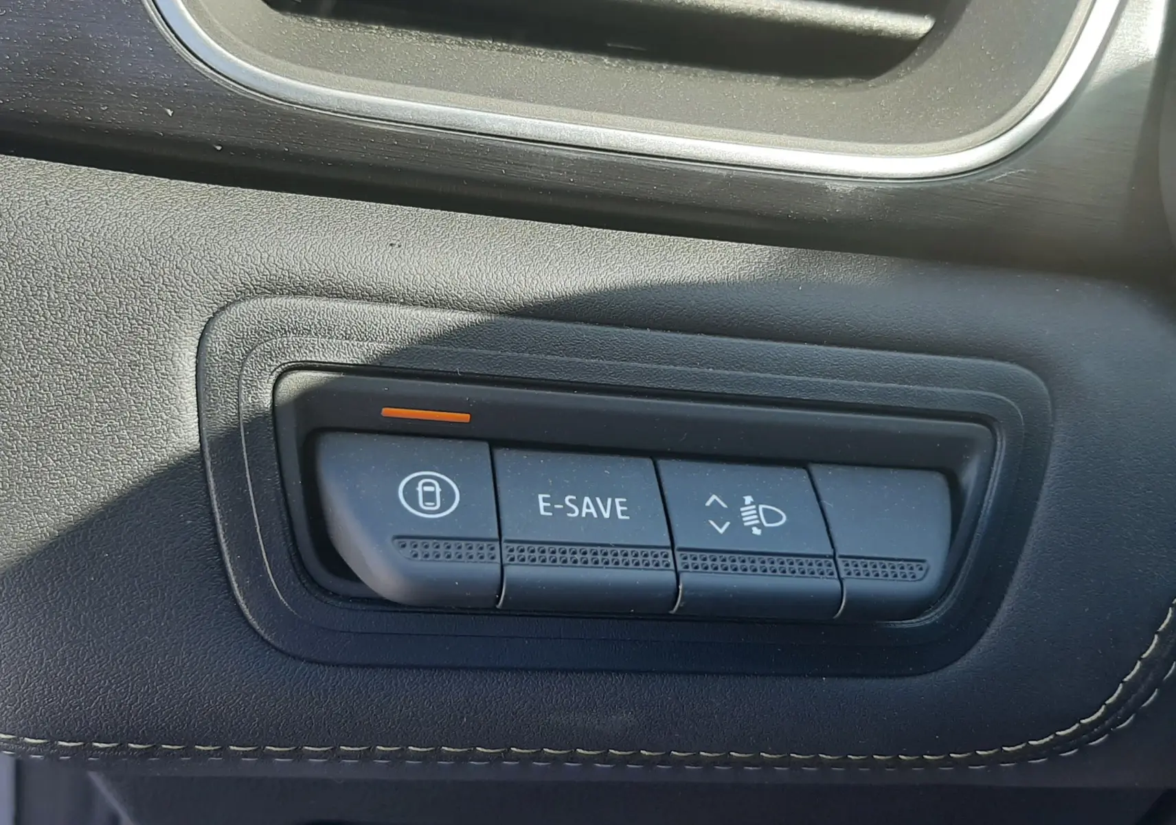 Gros plan sur les commandes E-SAVE et réglage des phares du tableau de bord noir du Renault Symbioz gris Cassiopée.