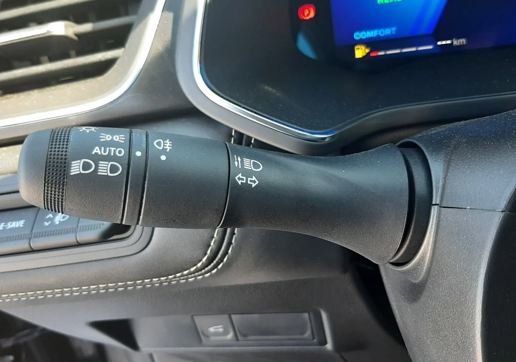 Gros plan sur la commande des feux et clignotants à gauche du volant dans l'habitacle noir du Renault Symbioz gris cassiopée.