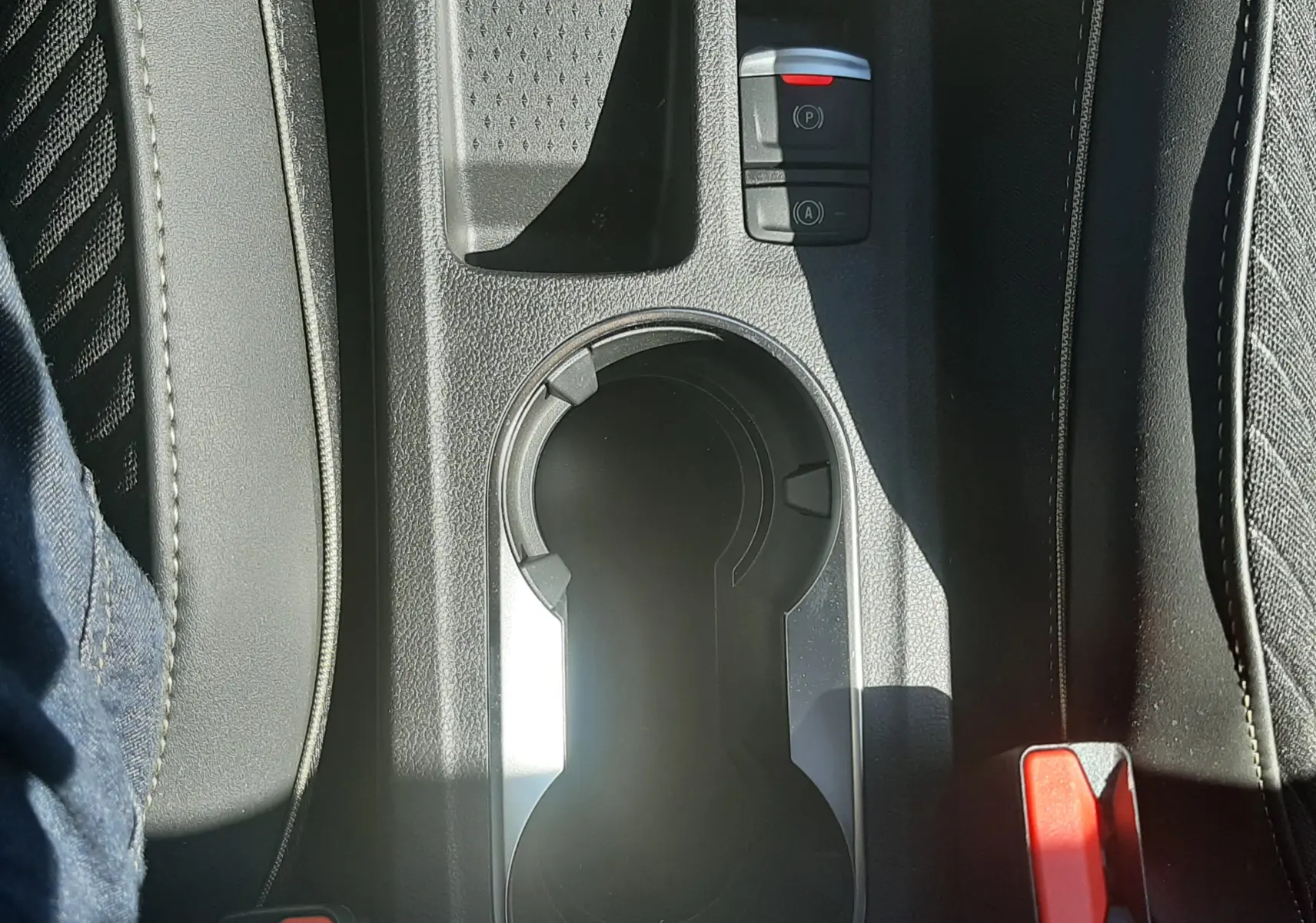 Gros plan sur la console centrale noire du Renault Symbioz 2025, avec porte-gobelets et boutons de frein à main électrique.