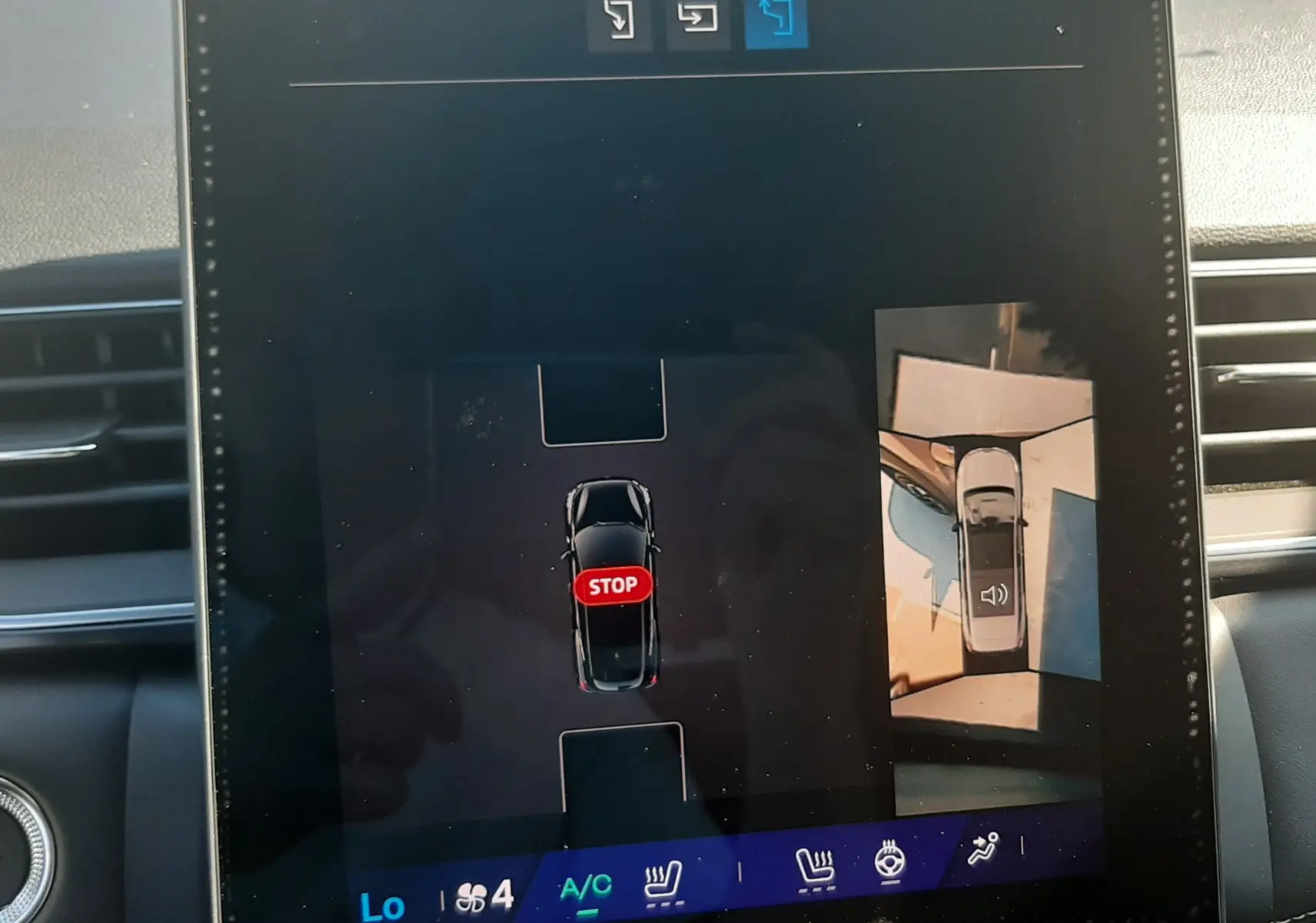 Écran tactile intérieur du Renault Symbioz gris cassiopée montrant l'aide au stationnement avec vue aérienne du véhicule.