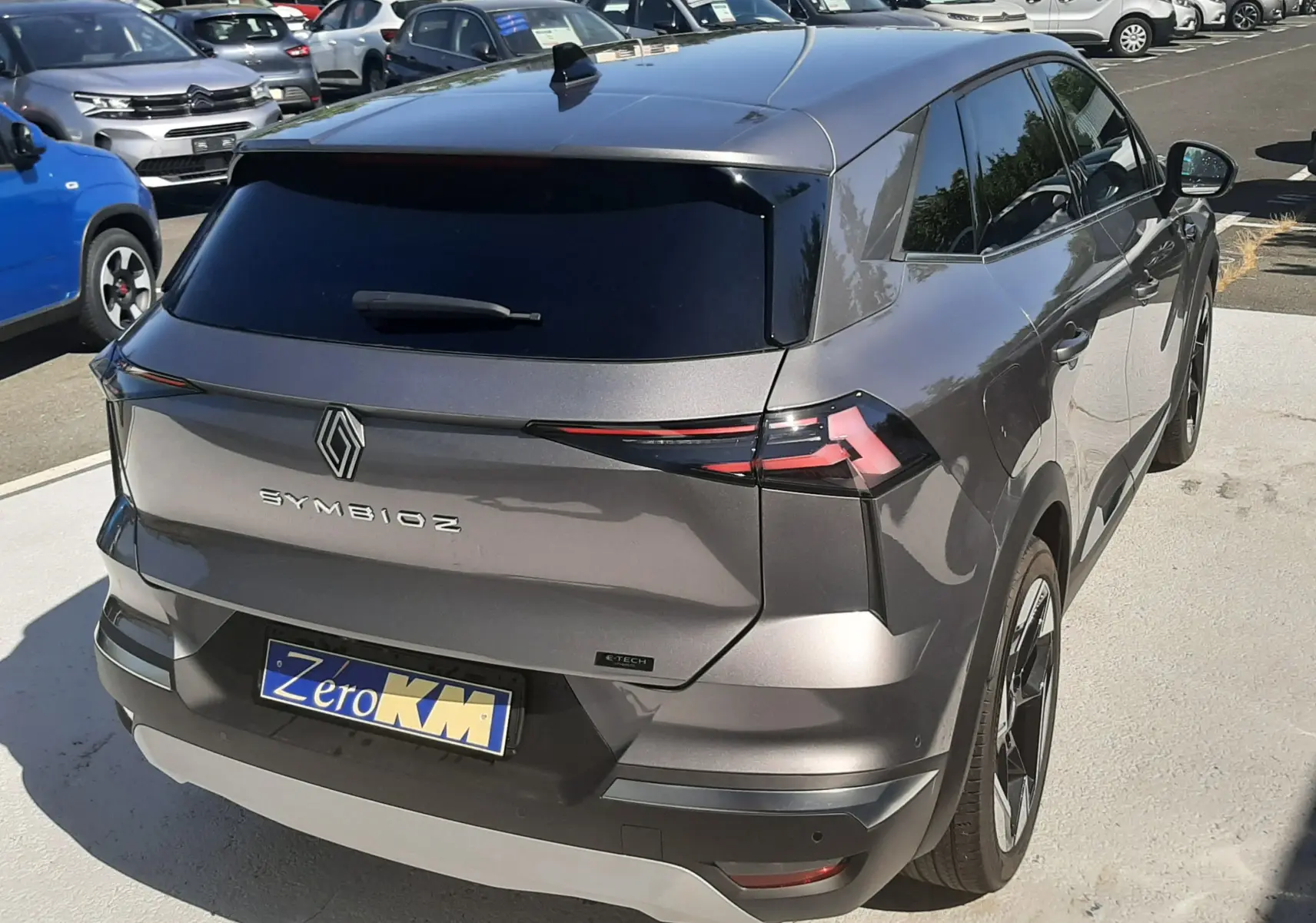 Vue 3/4 arrière d'une Renault SYMBIOZ gris cassiopée avec vitres teintées et feux arrière LED fins.