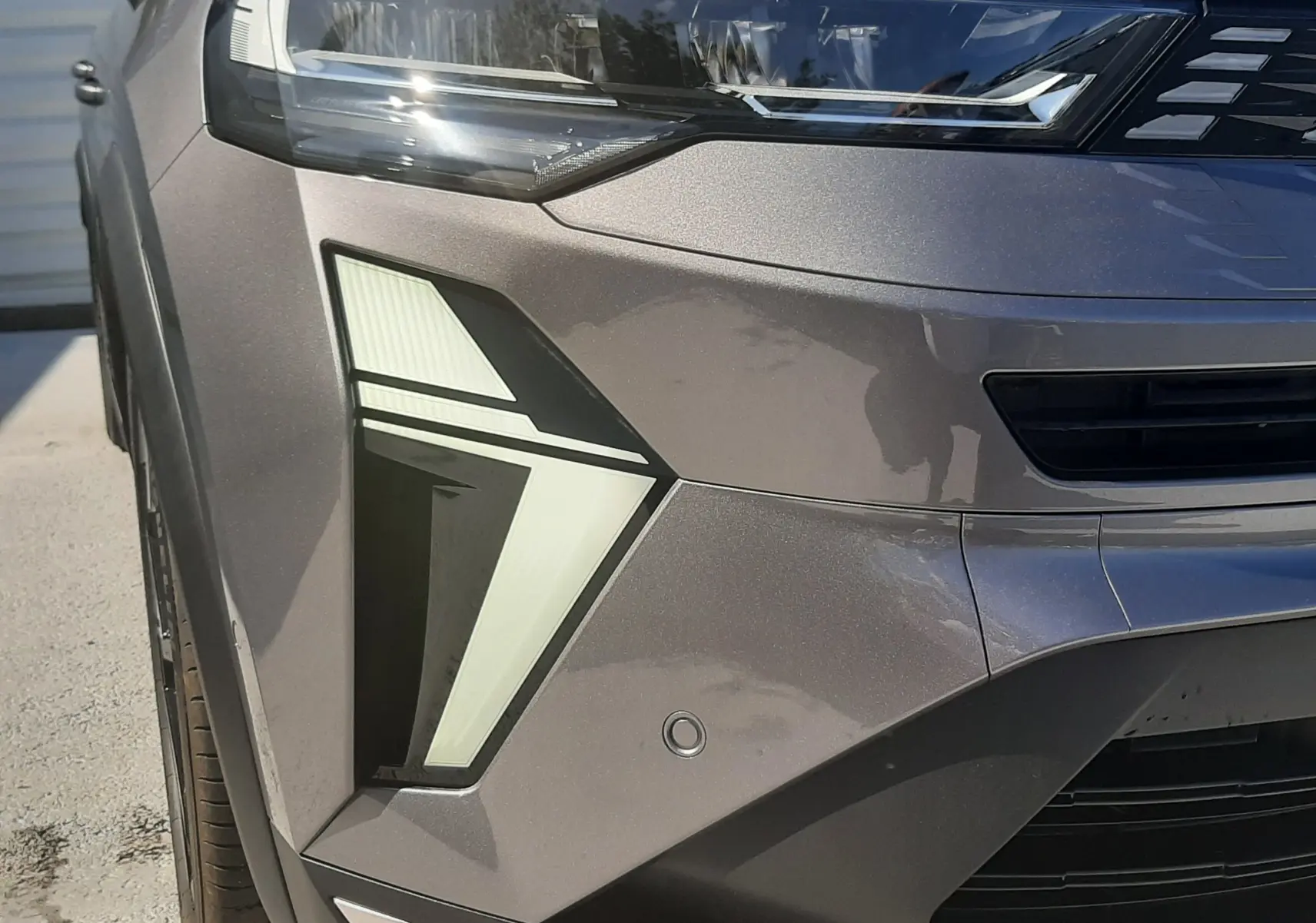 Gros plan sur le phare avant gauche du Renault Symbioz gris Cassiopée avec feux LED au design angulaire.