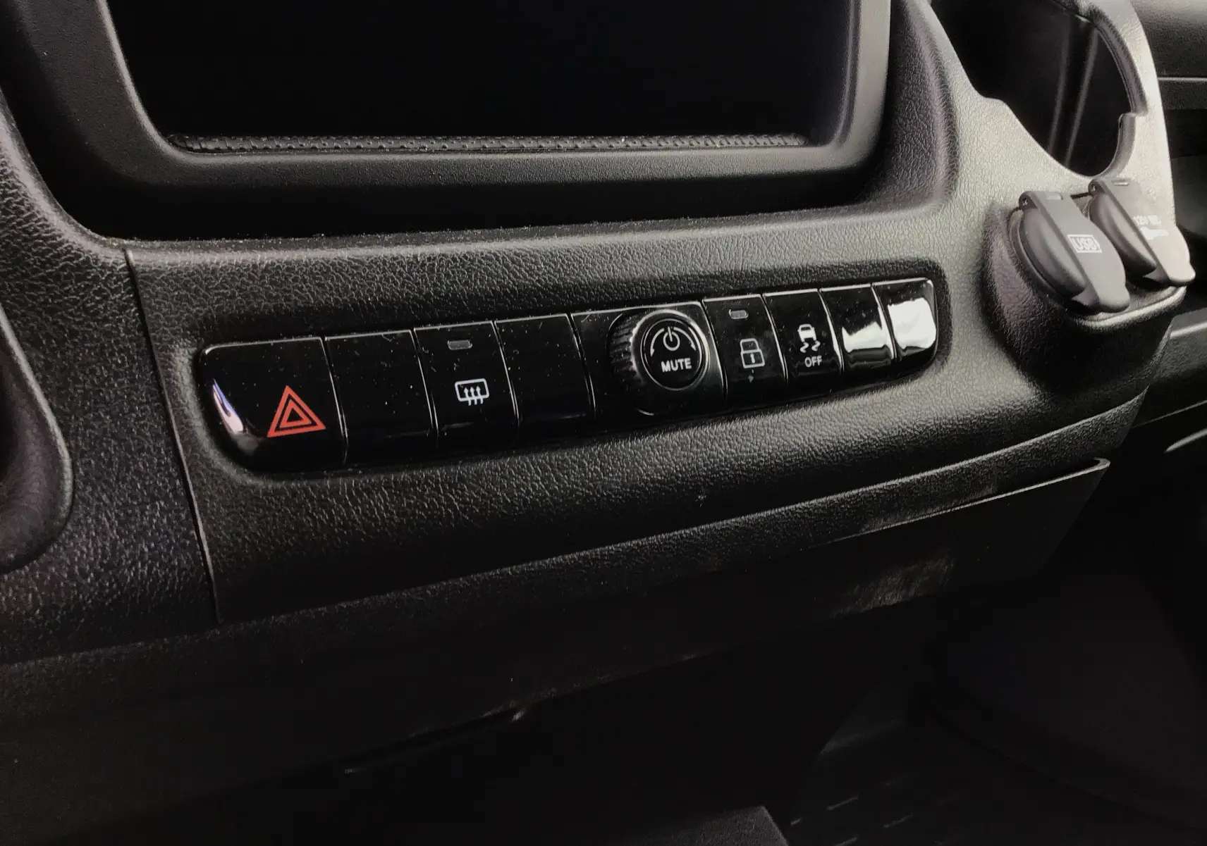 Gros plan sur la rangée de boutons noirs du tableau de bord du Fiat Ducato Fourgon blanc, version 2024.