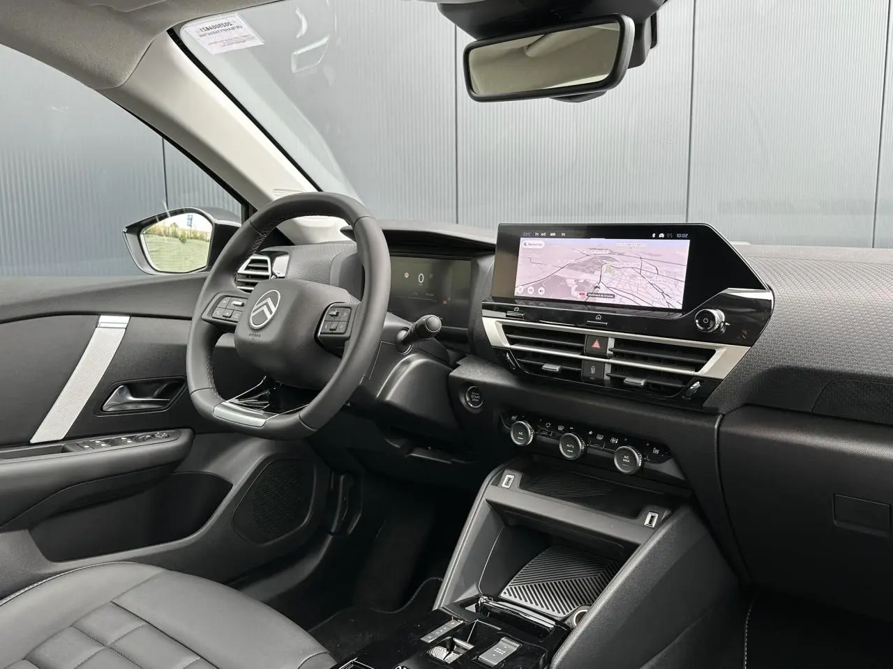 Intérieur avant droit de la Citroën C4 Manhattan Green 2025, tableau de bord avec écran tactile et volant cuir noir.