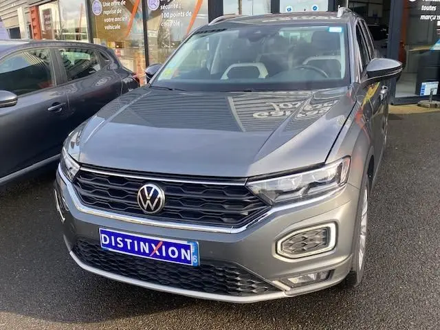 Volkswagen T-Roc gris Indium vu de face 3/4 avant droit, avec calandre noire et phares LED distinctifs.