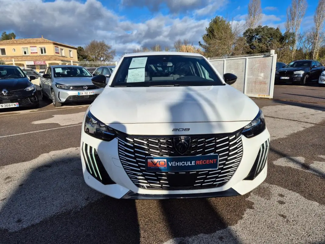 Vue avant d'une Peugeot 208 Hybrid 136 e-DCS6 GT blanche, avec calandre noire et feux diurnes LED verticaux.
