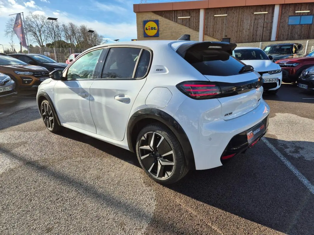 Peugeot 208 Hybrid blanc vue 3/4 arrière droit, jantes alliage 17 pouces et toit avec antenne requin.