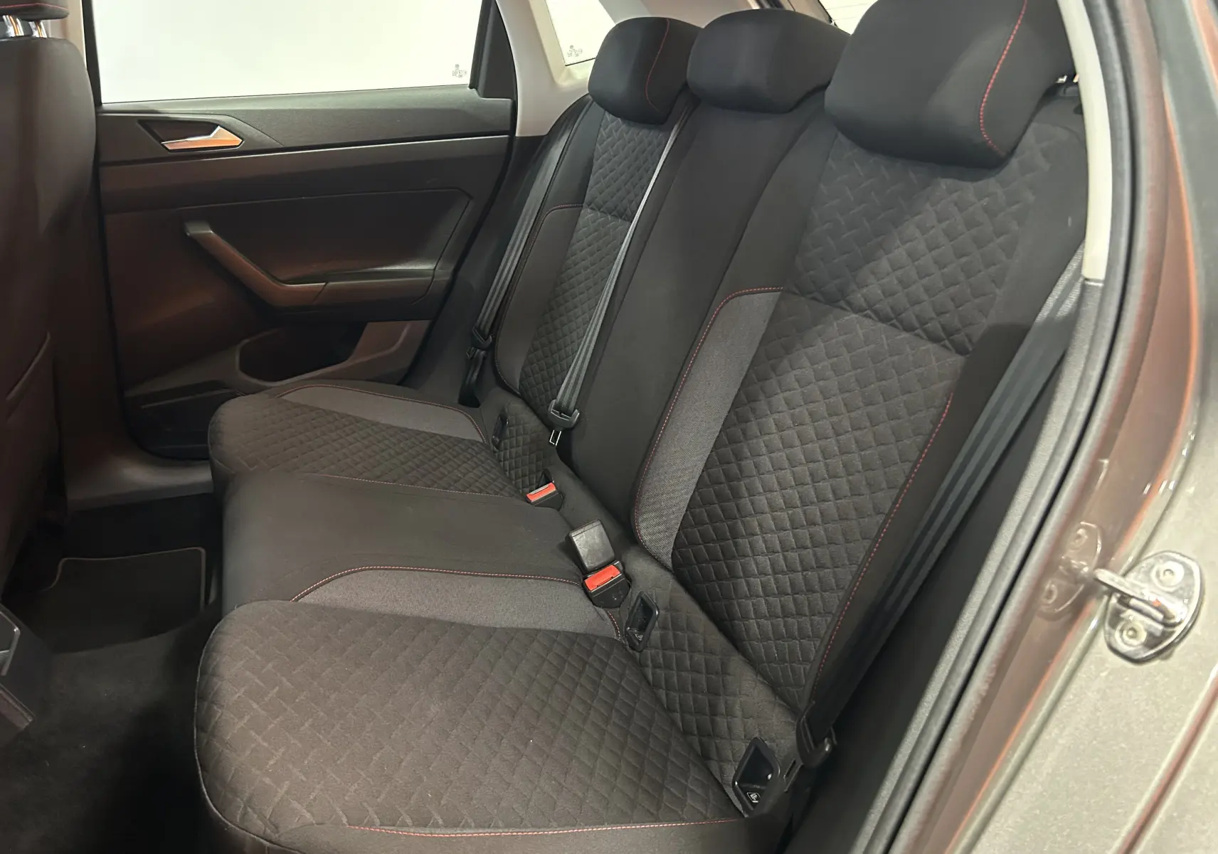 Vue intérieure côté droit des sièges arrière en tissu noir avec surpiqûres rouges d'une Volkswagen Polo gris 2018 à 5 portes.