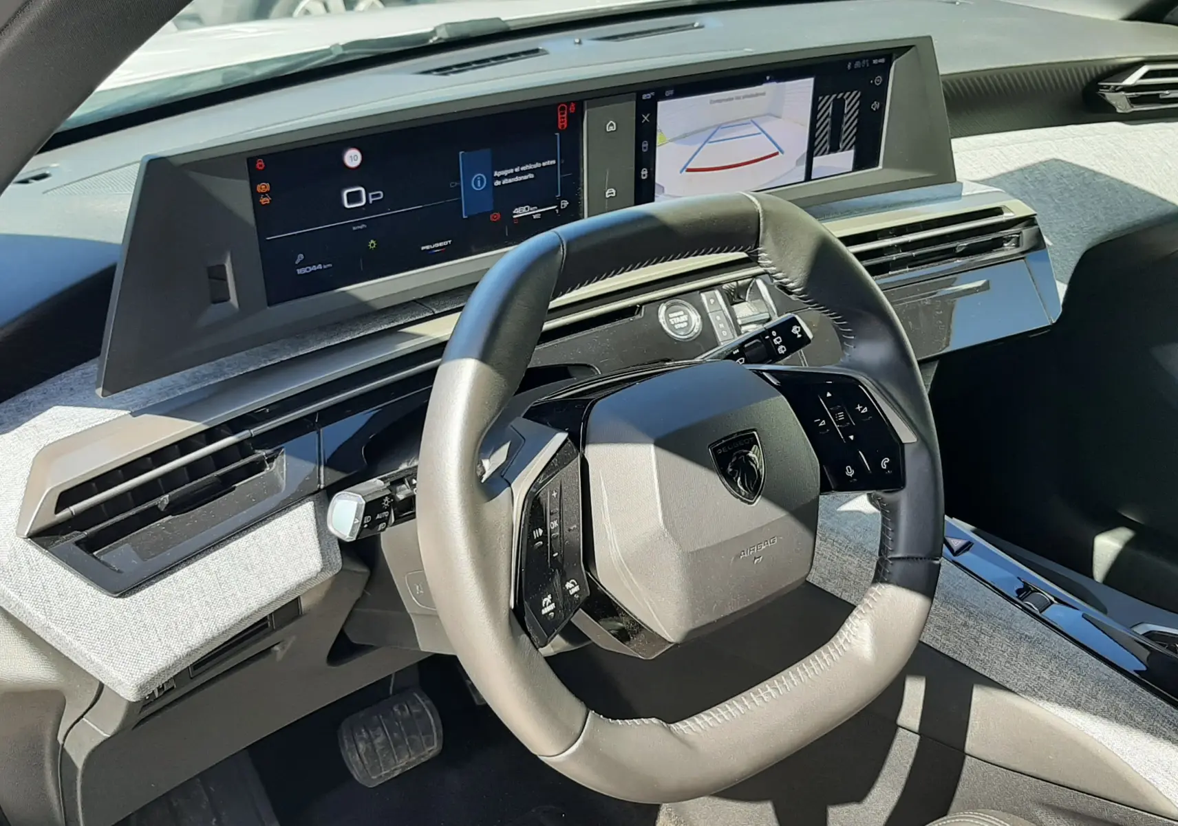 Vue intérieure du poste de conduite du Peugeot 5008 Hybrid 2025, avec tableau de bord numérique et volant compact noir.