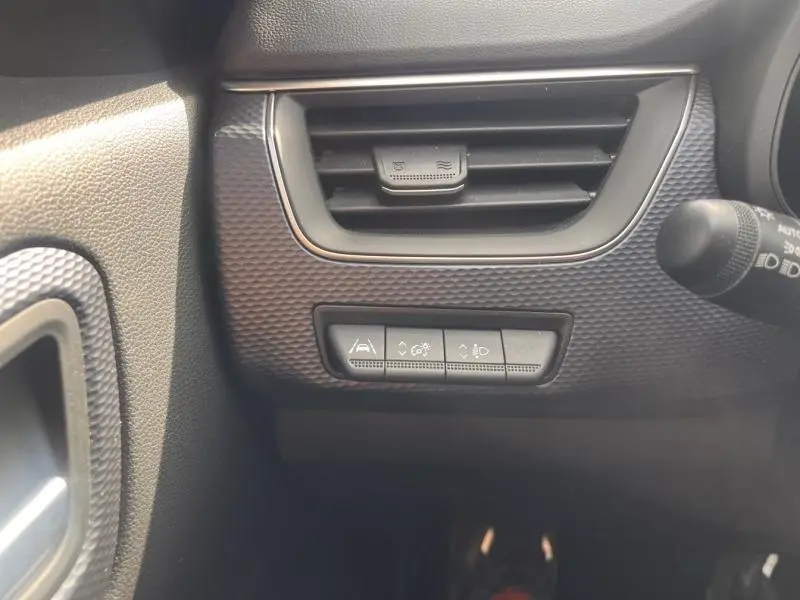 Vue rapprochée du tableau de bord côté gauche du Renault Arkana blanc perle, avec grille d’aération et commandes d’assistance.