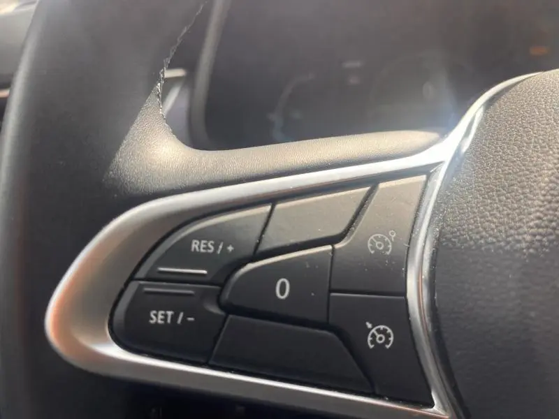 Gros plan sur les commandes de régulateur de vitesse au volant cuir noir du Renault Arkana blanc perle.