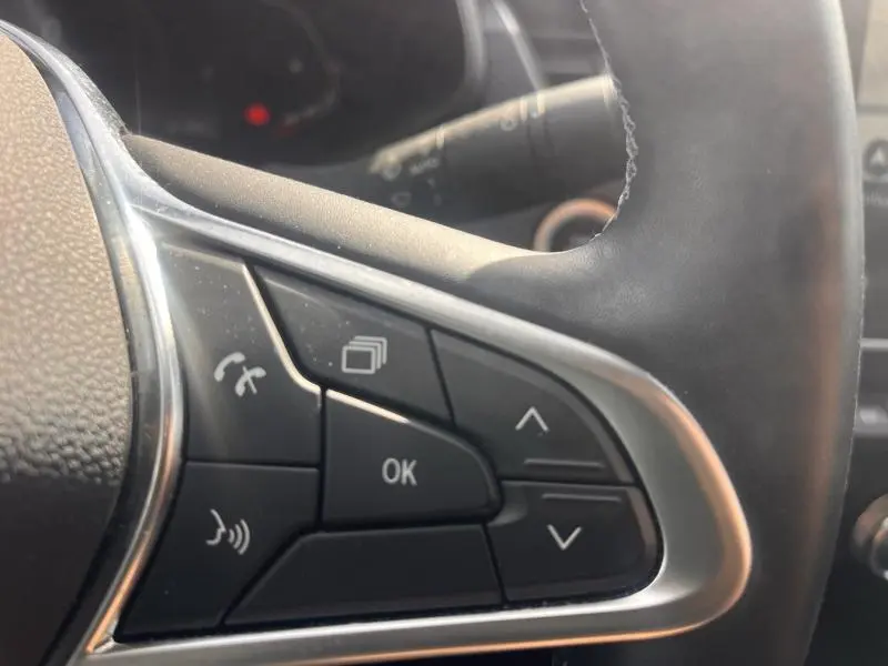 Gros plan sur les commandes multifonctions noires du volant cuir du Renault Arkana blanc perle 2023, côté gauche.