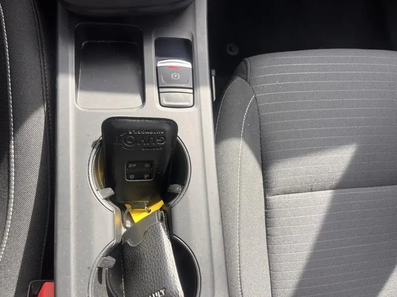 Vue rapprochée de la console centrale grise avec porte-clés Renault et siège tissu noir côté droit visible.