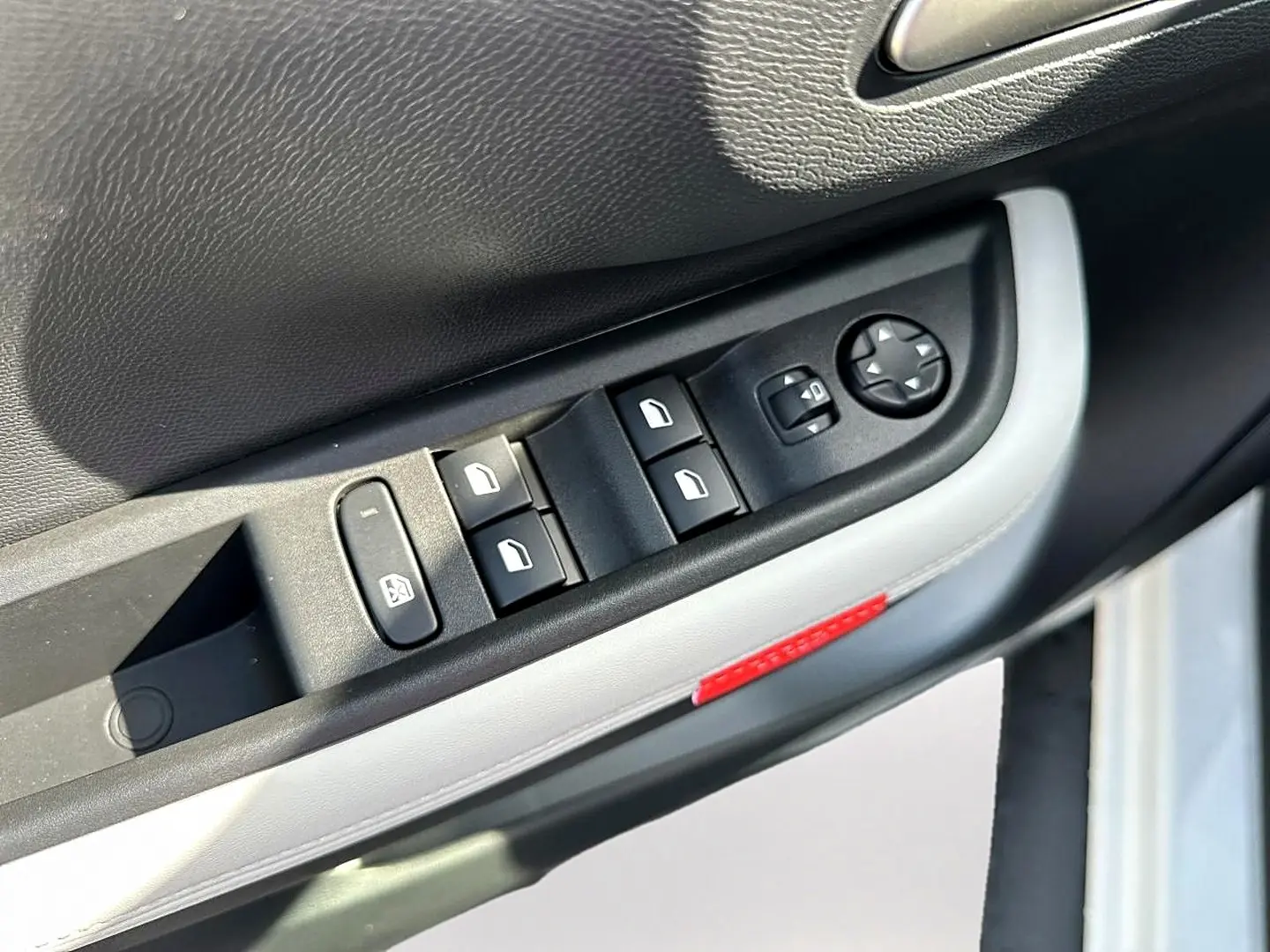 Gros plan sur la commande des vitres électriques côté conducteur d'une Citroën C3 Aircross blanche, avec bouton de réglage des rétroviseurs.
