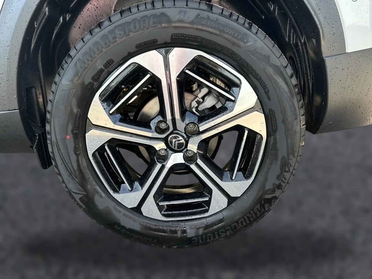 Gros plan sur la jante alu bicolore noire et argentée du côté avant droit du Citroën C3 Aircross blanc.
