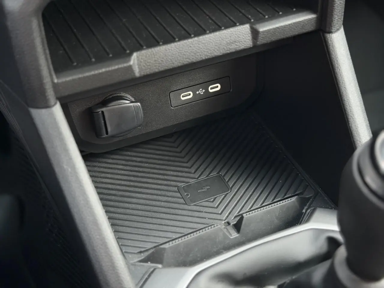 Gros plan sur la console centrale noire du Dacia Duster 2025, montrant la zone de charge à induction avec ports USB.