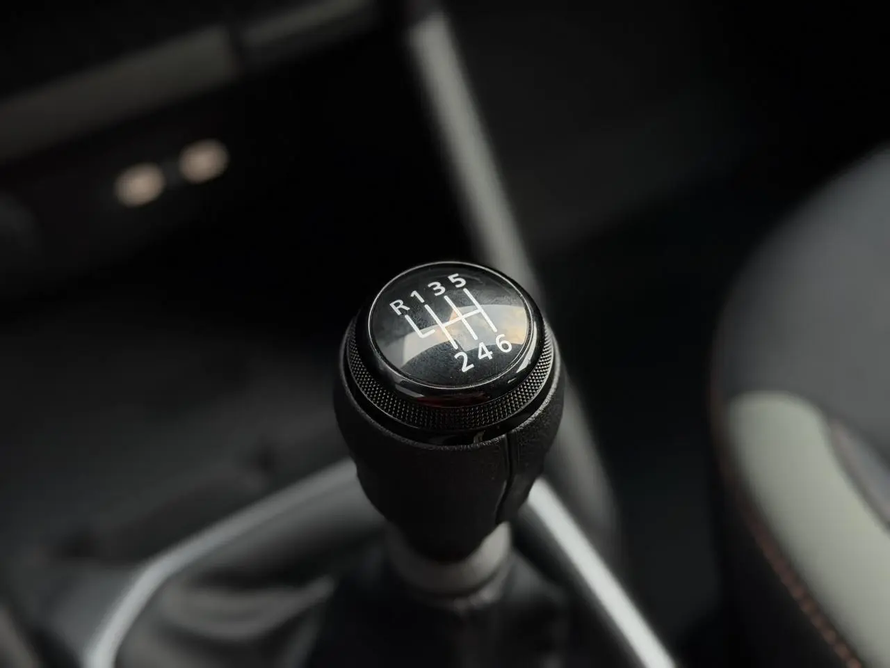 Gros plan sur le levier de vitesses manuel du Dacia Duster TCE 4x2 MHEV 130, intérieur sombre avec surpiqûres brun cuivré.