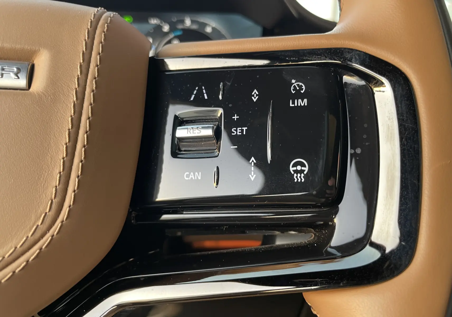 Gros plan sur les commandes de régulateur de vitesse sur le volant en cuir brun du Range Rover Sport 2023.