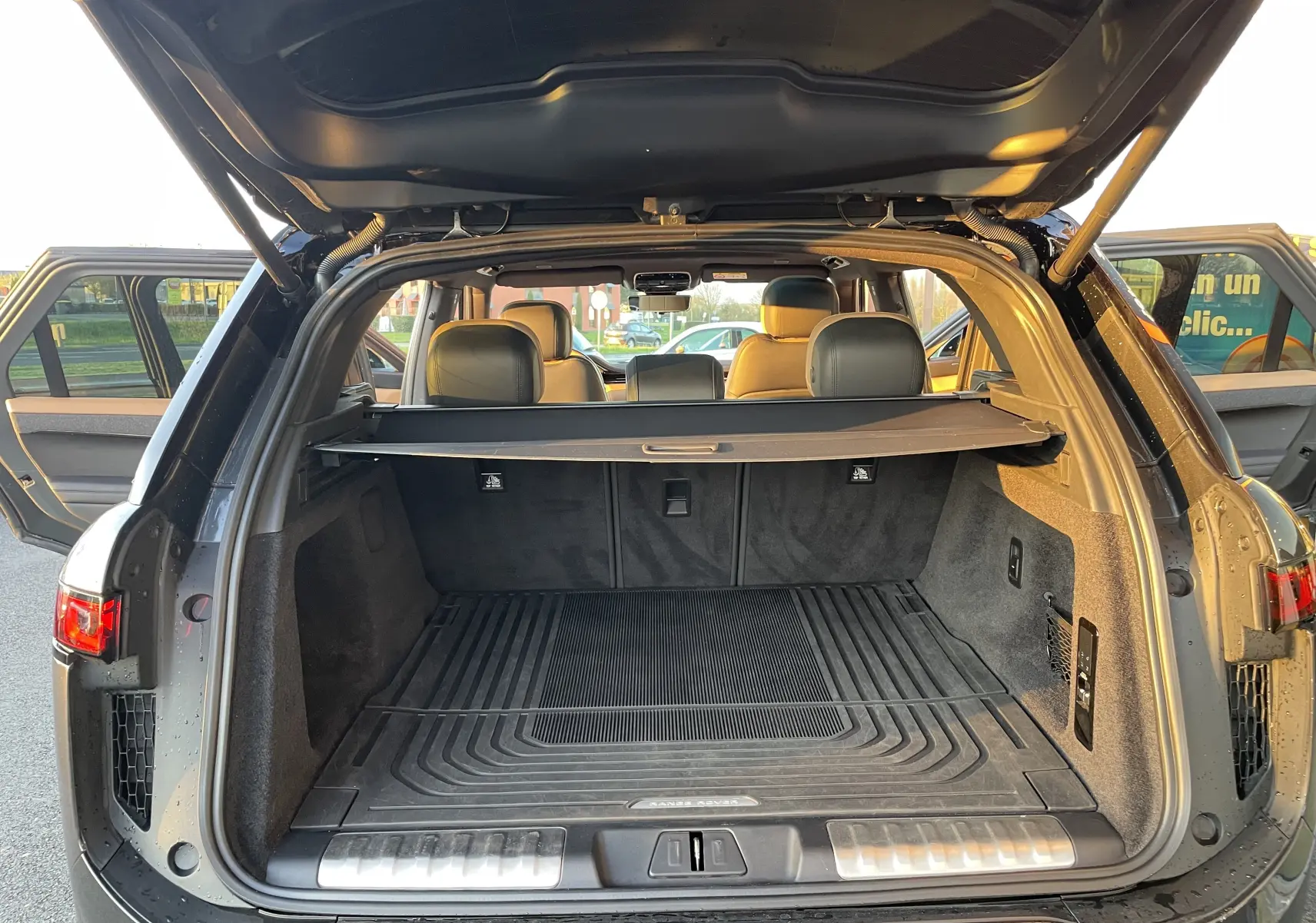 Vue arrière du coffre ouvert d’un Range Rover Sport P440 HSE R-Dynamic gris Carpathian avec intérieur cuir Caraway/Ebony.