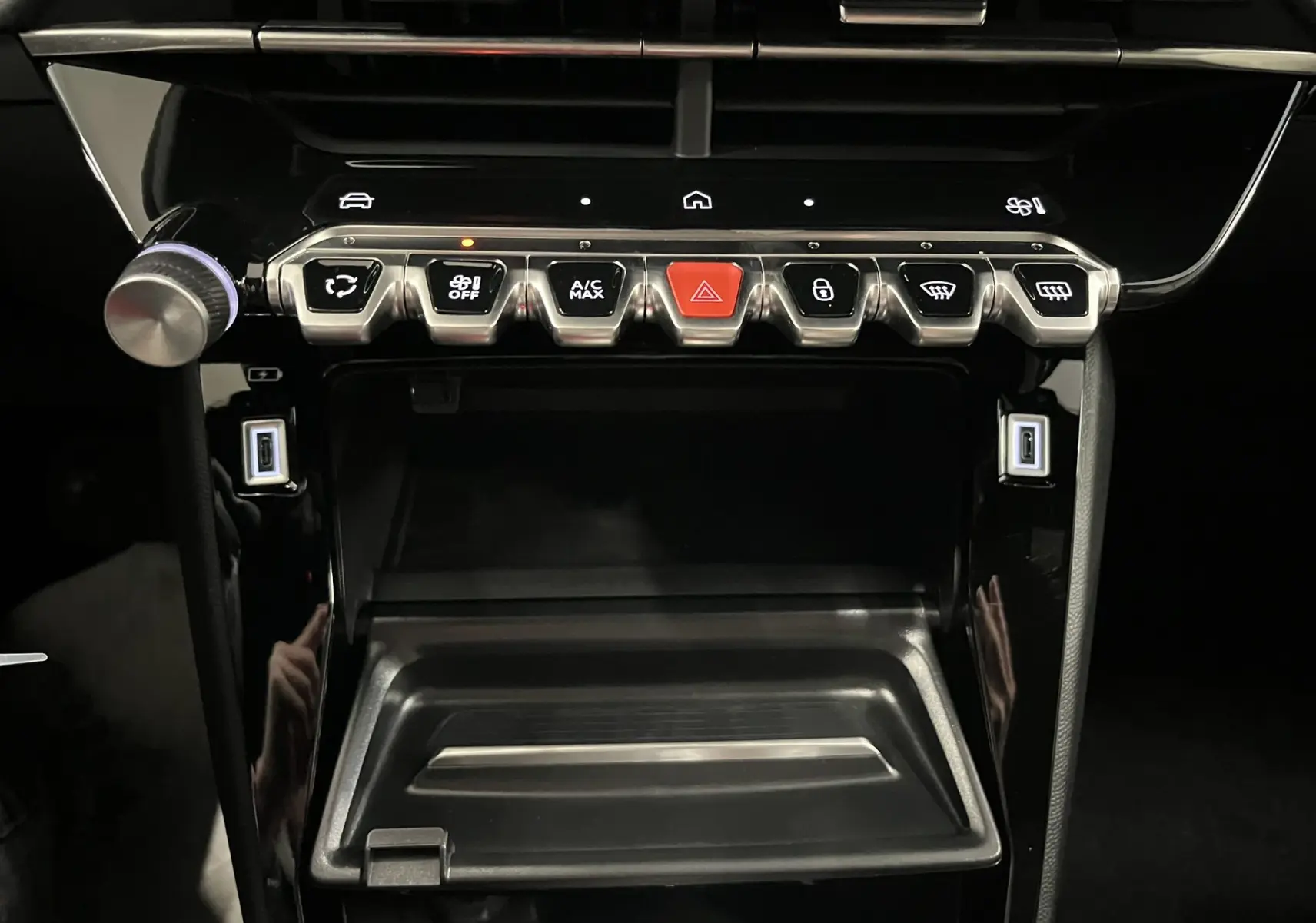 Vue rapprochée de la console centrale noire brillante du Peugeot 2008 1.2 Hybrid 145ch avec boutons de commande et ports USB.
