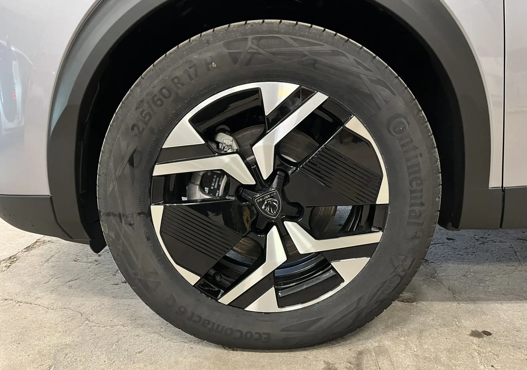 Gros plan sur la roue avant droite du Peugeot 2008 gris Artense, mettant en valeur la jante noire et argentée au design moderne.