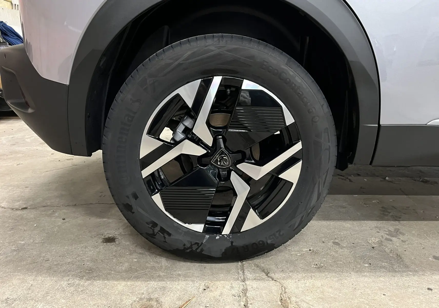 Gros plan sur la roue avant droite du Peugeot 2008 gris Artense Métal avec jante alliage bicolore noire et argentée.