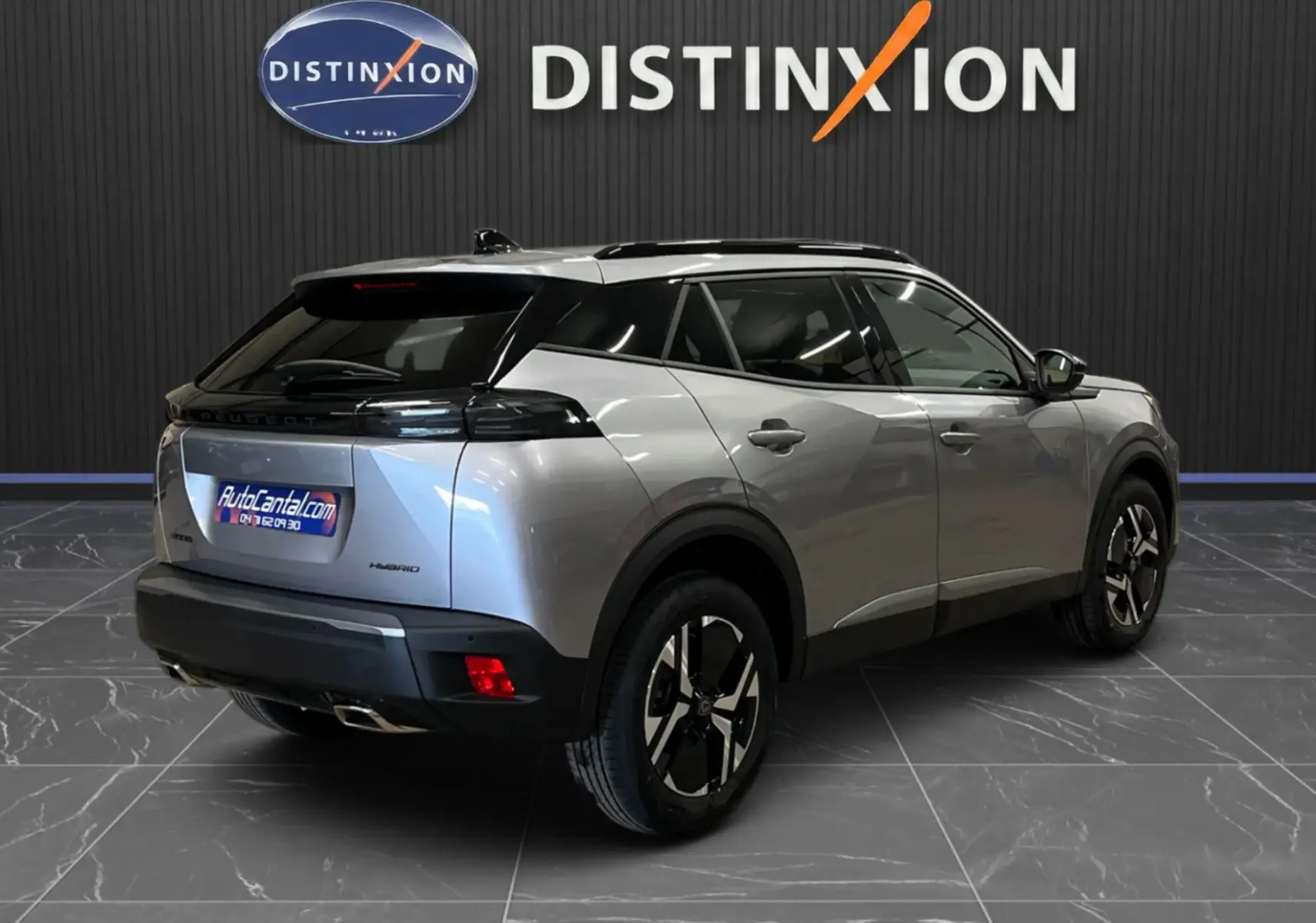 Peugeot 2008 gris Artense métal en 3/4 arrière droit, toit noir et jantes bi-ton visibles en intérieur showroom.