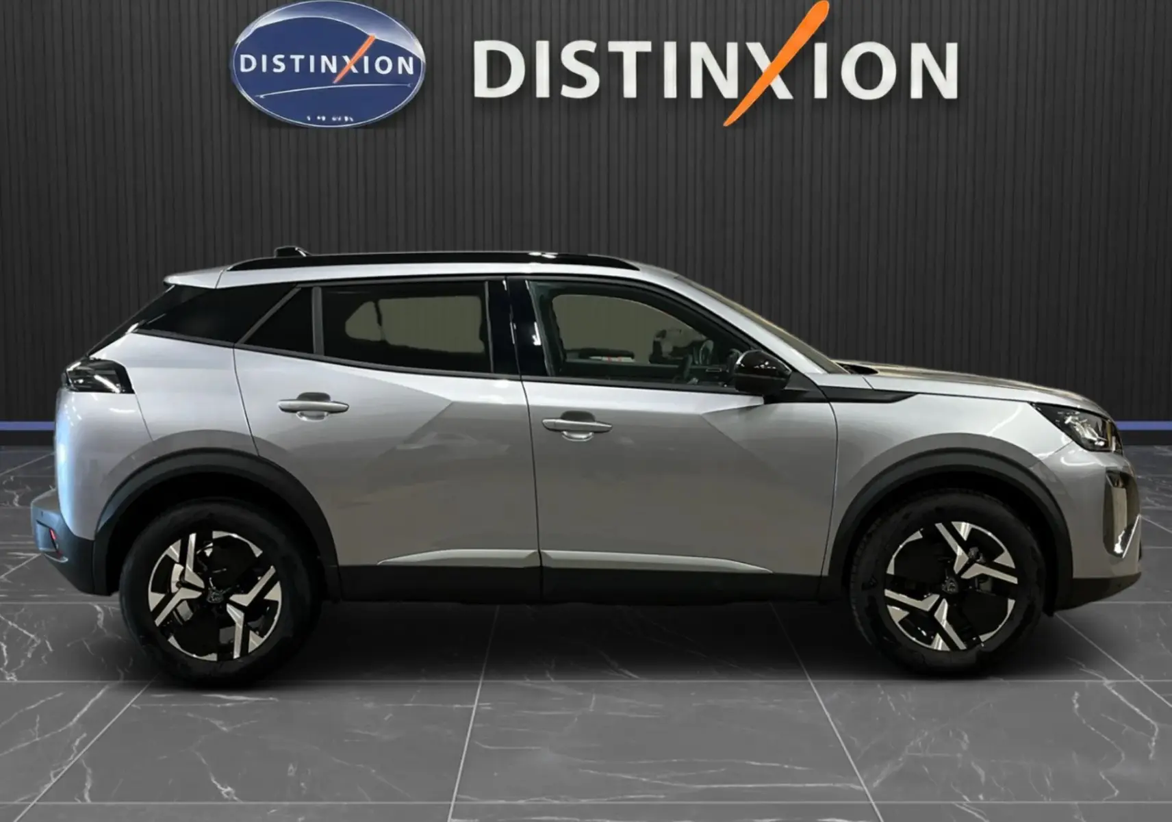 Peugeot 2008 gris Artense métal en profil droit, soulignant ses jantes bicolores et toit noir panoramique.